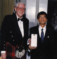 Dinner chairman Neil Fraser presenting one of the door prizes (Dalwhinnie Single Malt) to Arthur Lee